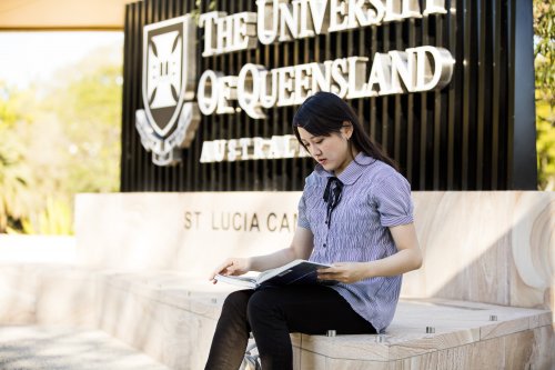 クイーンズランド大学セントルシアキャンパスの看板の前に座る学生