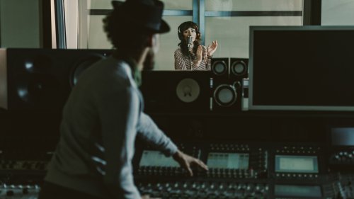 録音スタジオのコンソールでボーカル録音を進めるエンジニア