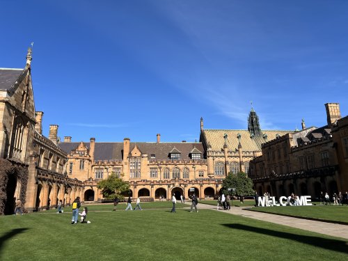 シドニー大学のメイン・クアドラングルと芝生の広場で過ごす学生