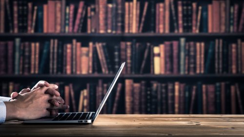 書架を背にノートパソコンで書類を作成する手元