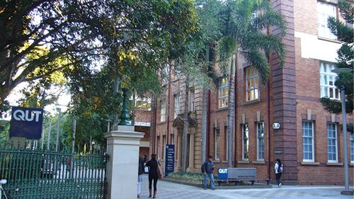 QUT（クイーンズランド工科大学）Gardens Pointキャンパスの入り口。QUTの看板が掲げられた門を学生が行き交う様子